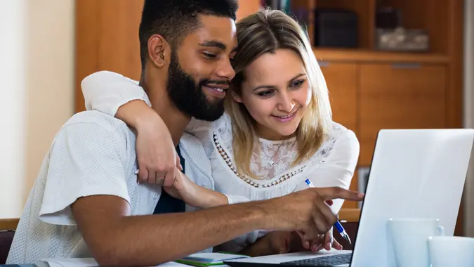 Young couple filling forms of banking application in domestic interior.