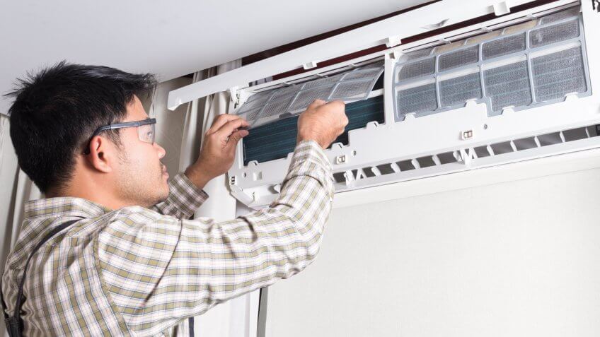 Technician cleaning filter of air conditioner system at home.