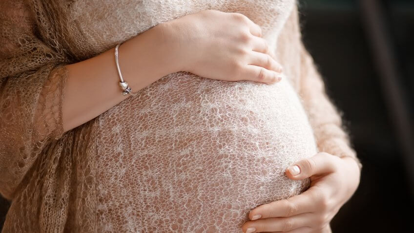 woman holding her stomach in soft maternity clothes