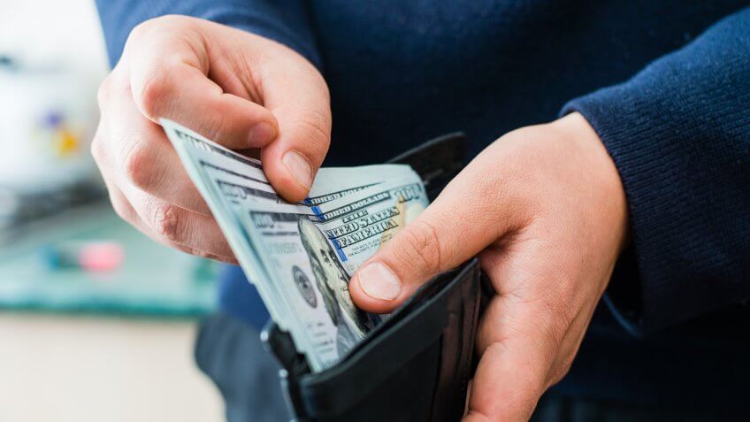 man pulling $100 cash money out of his wallet