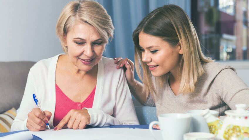 Adult daughter helps her mother to lead home accounting.