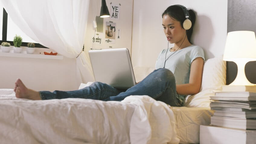 asian college student on her bed on her laptop