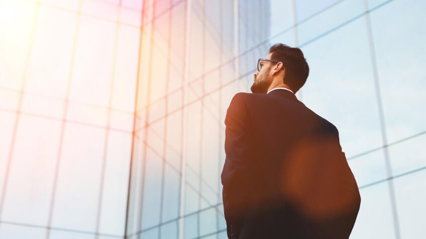 suited man with glasses looking out into the distance