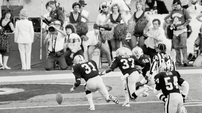 Los Angeles Raiders' Derrick Jensen (31), Lester Hayes (37) and Kenny Hill (48) chase a blocked punt into the end zone where they recovered it for a touchdown during first quarter action in super Bowl XVIII against the Washington Redskins, in Tampa Stadium.