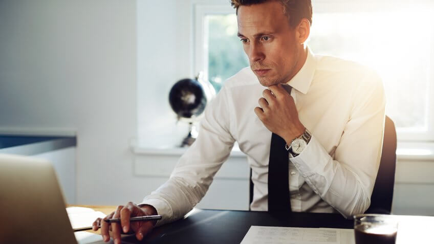 suited inquisitive man looking at his laptop