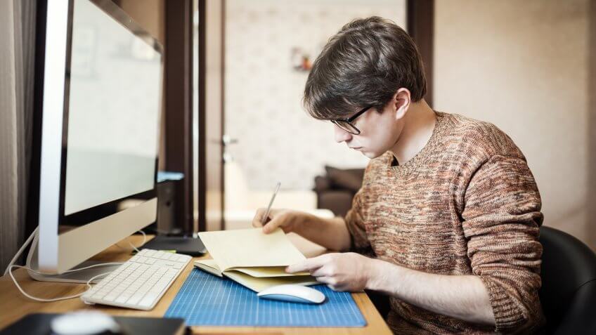 young person journaling in front of their computer