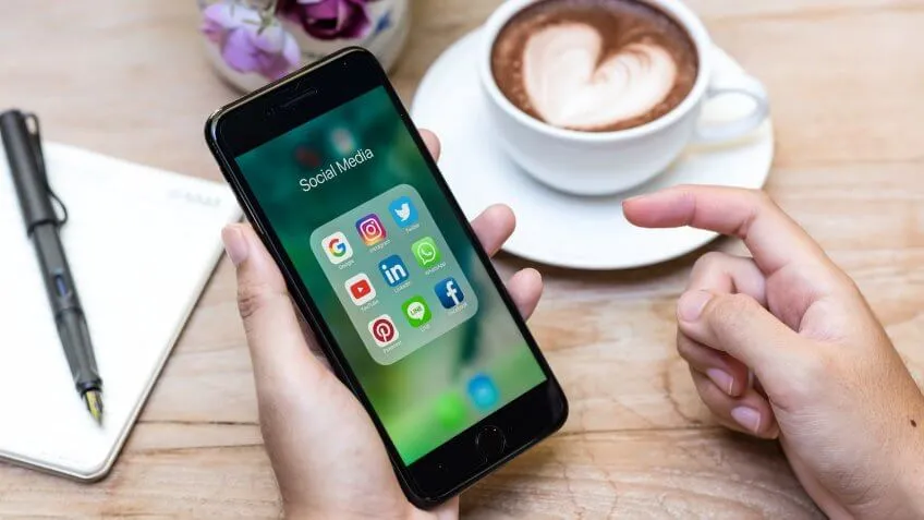 Close up of woman's hands at a coffee shop checking her social media