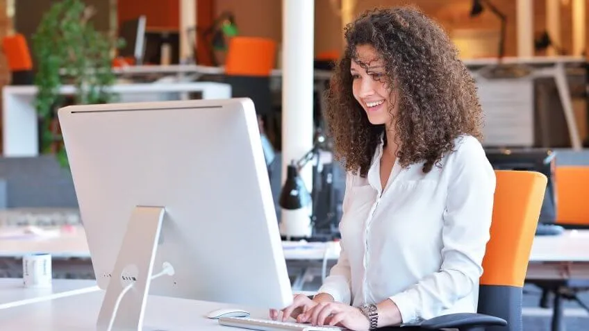 Woman happily typing on her computer