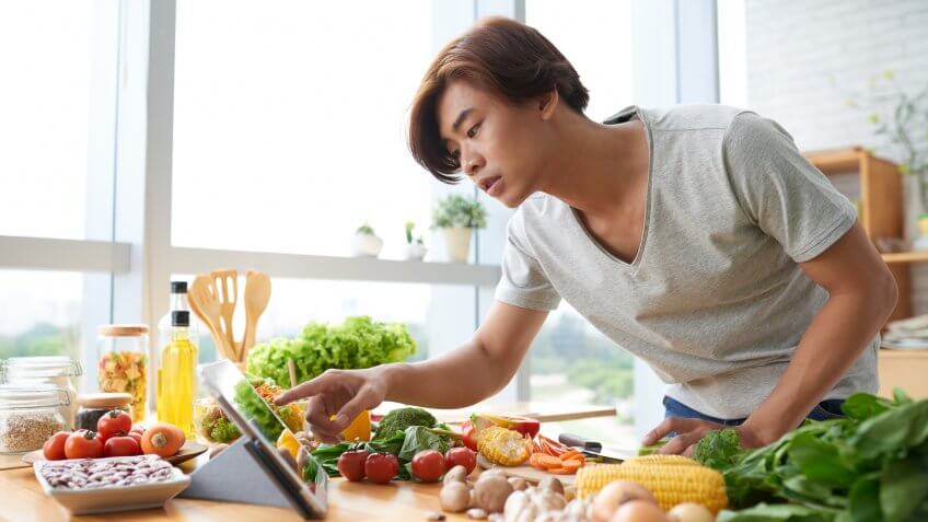 young man reading a recipe with ingredients laid out