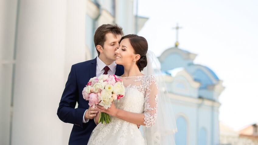 bride and groom posing outside of a church