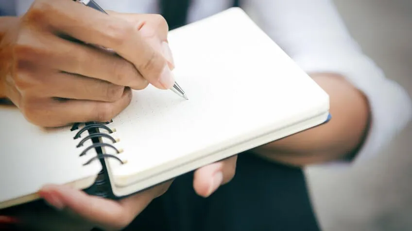 man writing in his notebook