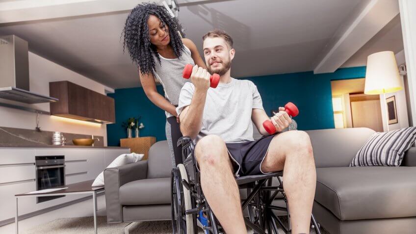 man in wheelchair working out with woman behind him