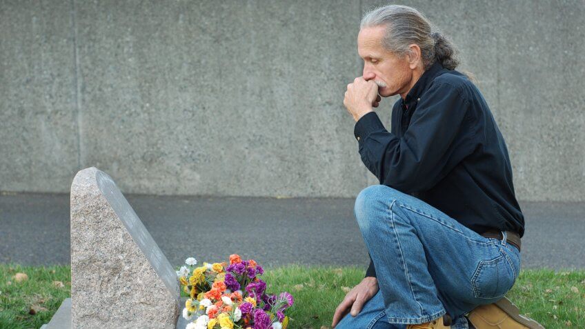 man mourning over a tombstone