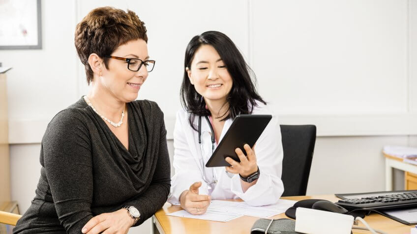 two women in the office looking happily at a tablet ipad together