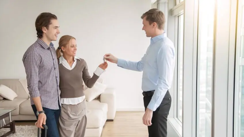 man handing a young couple house keys