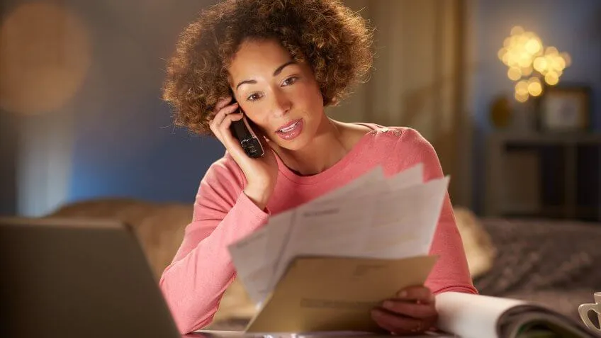 a young woman sits at home , going through her paperwork and bills .