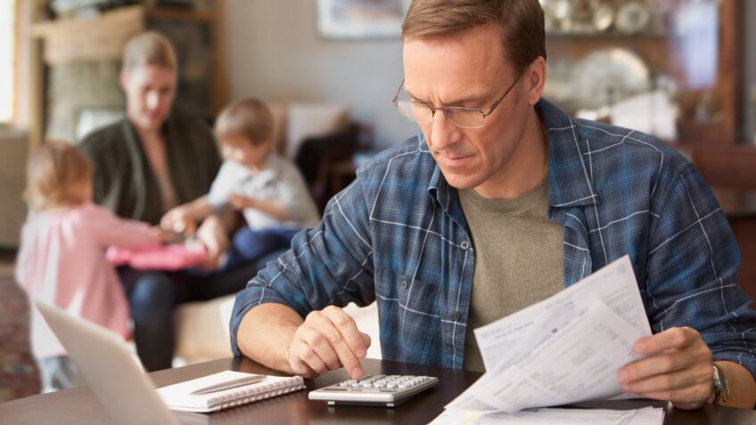 Father paying bills with family behind him.