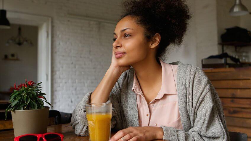 woman drinking orange juice looking out a window