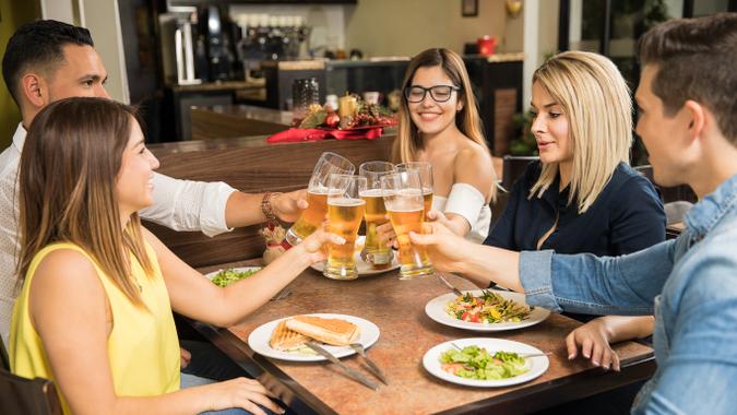 group of friends dining together clinking beer pints