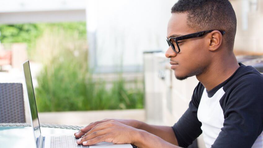 man typing on his laptop outside