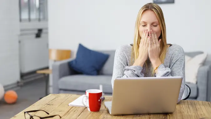 woman looks shocked with her laptop open