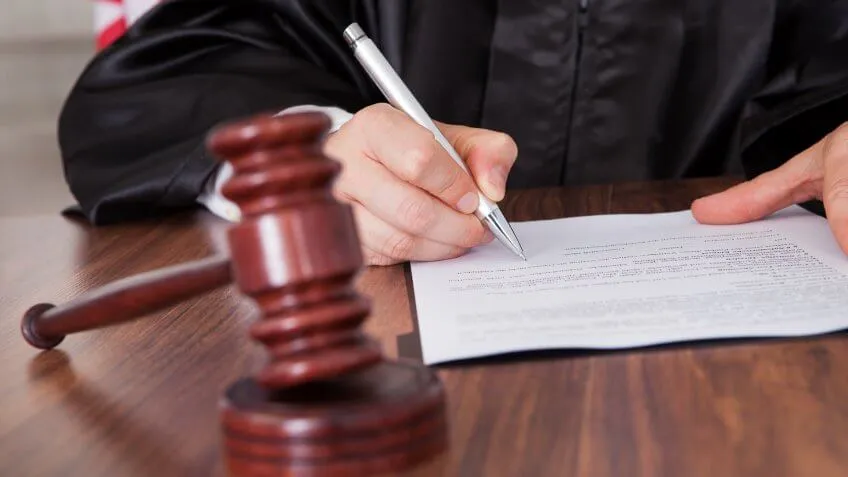 Close-up Of Male Judge Writing On Paper In Courtroom.