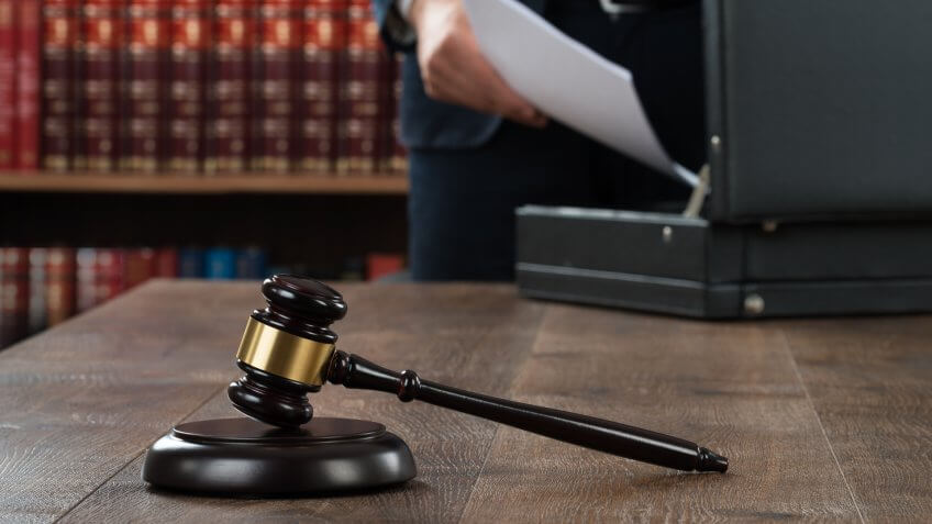 gavel with man rummaging through is briefcase in the back