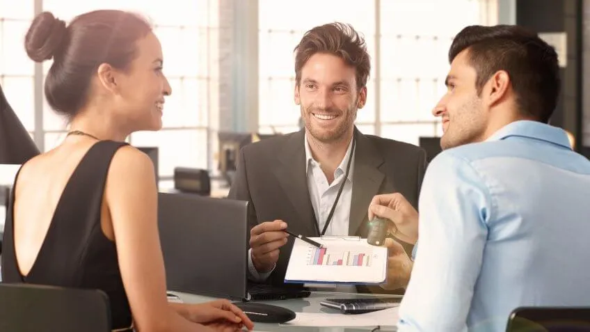 adviser pointing to a chart with a young man and woman looking at each other
