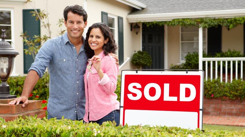 couple standing in front of a sold home
