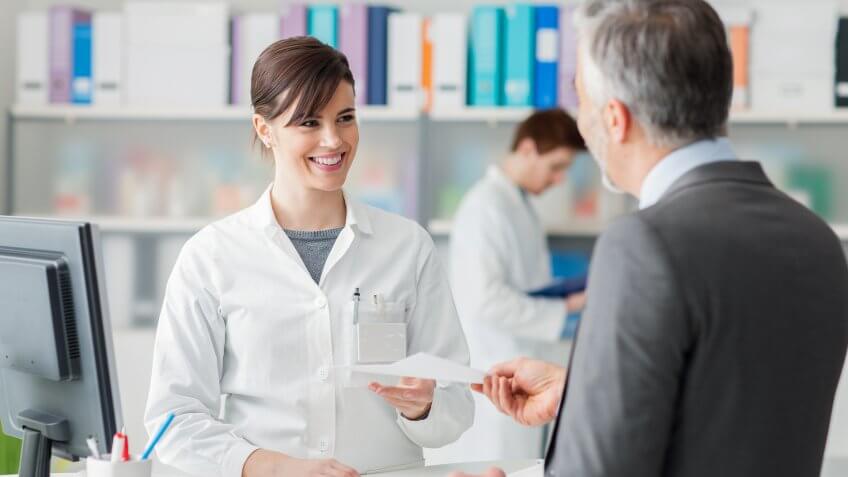 pharmacist handing a script to a man