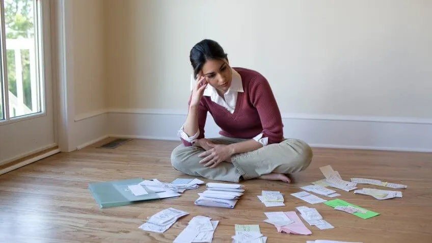Woman looking at bills and receipts on floor.