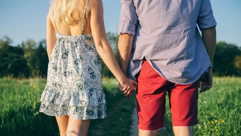 man and woman holding hands in a field