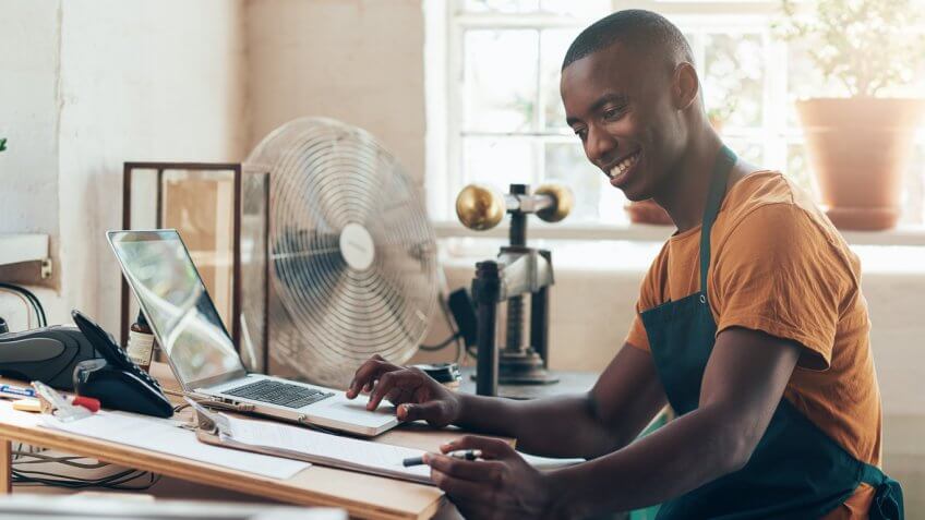 man looking at his laptop and clipboard