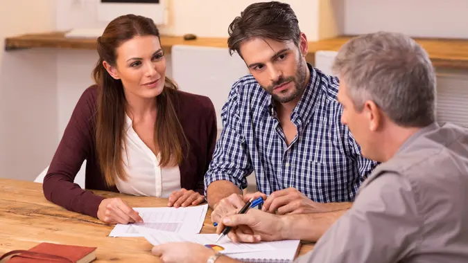 Businessman explaining loan policy to young couple.