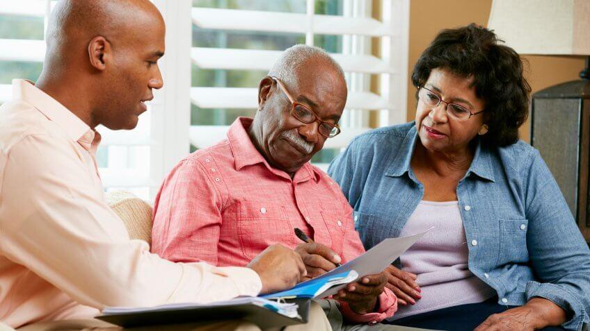 senior older couple filling out paperwork with younger man