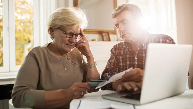 Senior couple sitting at home and having problems with paying their bills.
