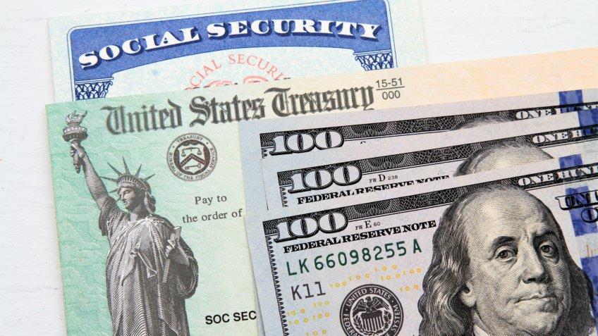 Partial view of Social Security card, US Treasury checks and hundred dollar bills.