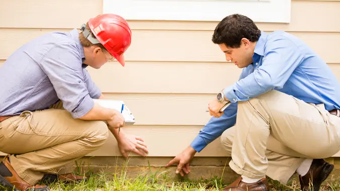 examining a home's exterior wall and foundation