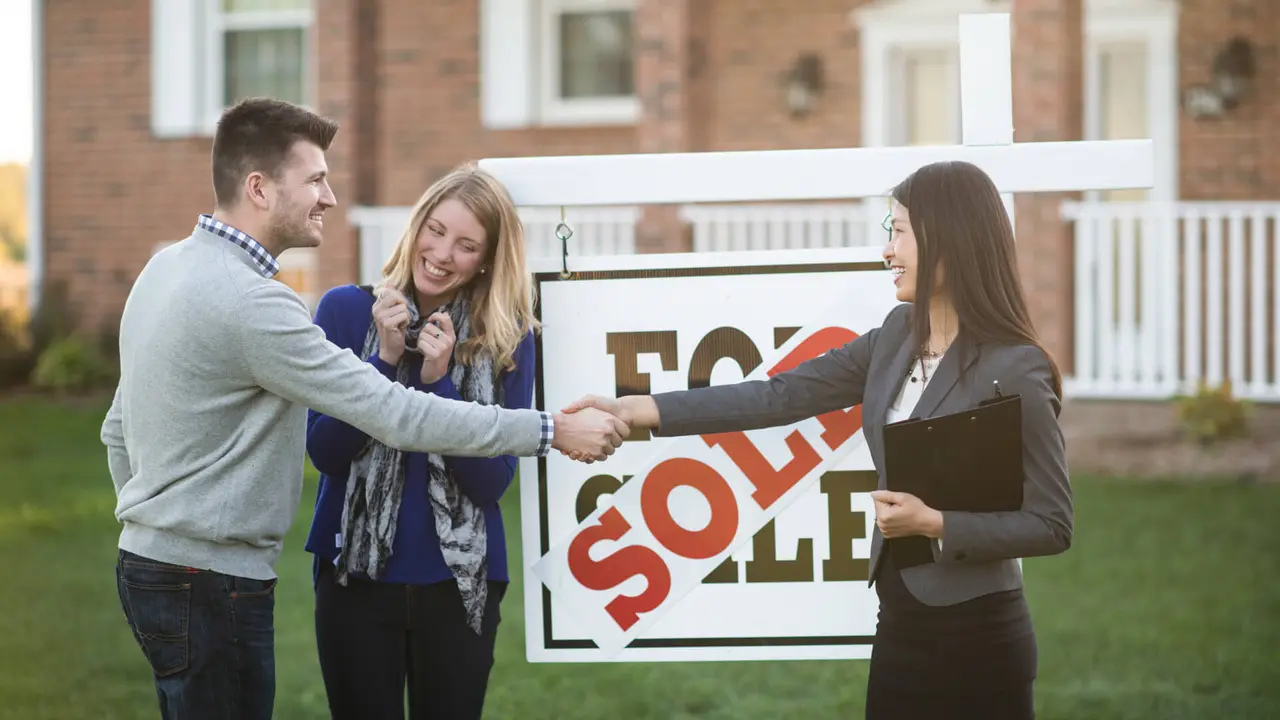 husband and wife are standing outdoors in front of their new house