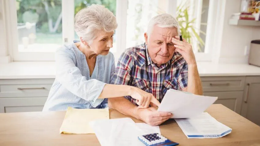 older senior retired couple looking over paper documents