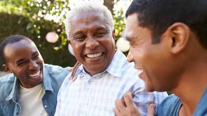 Senior man talking with his adult sons in garden, close up.