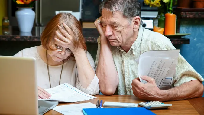 Senior couple at home reacting to many bills.