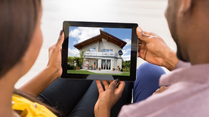 Couple Looking At House On Digital Tablet.