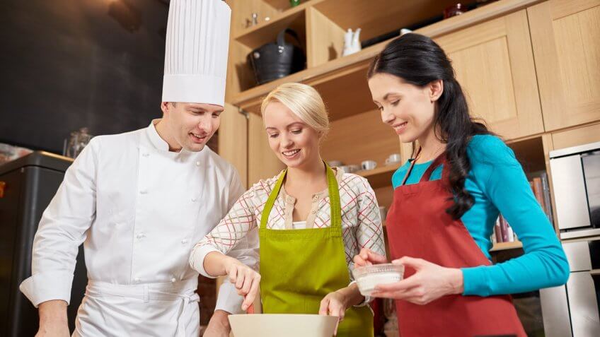 professional chef teaching two women how to cook