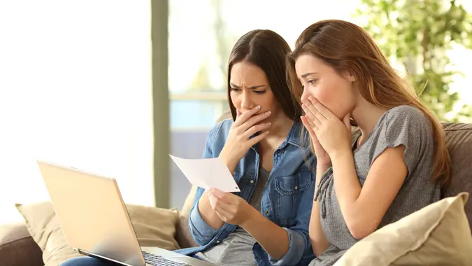 two women looking upset at a piece of paper