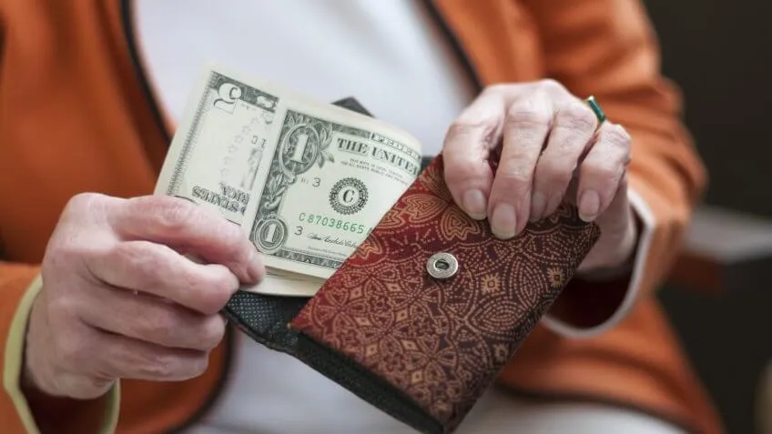 elderly older woman pulling money cash out of her wallet