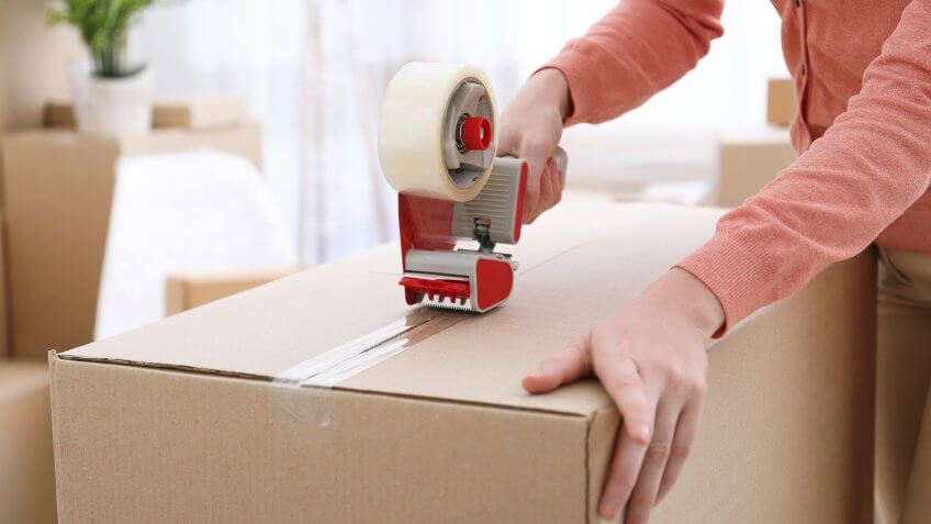 woman using packing tape on a moving box