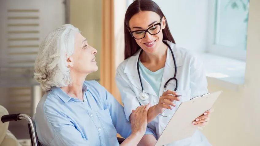 doctor with her clipboard speaking to an elderly senior retired woman in a wheelchair