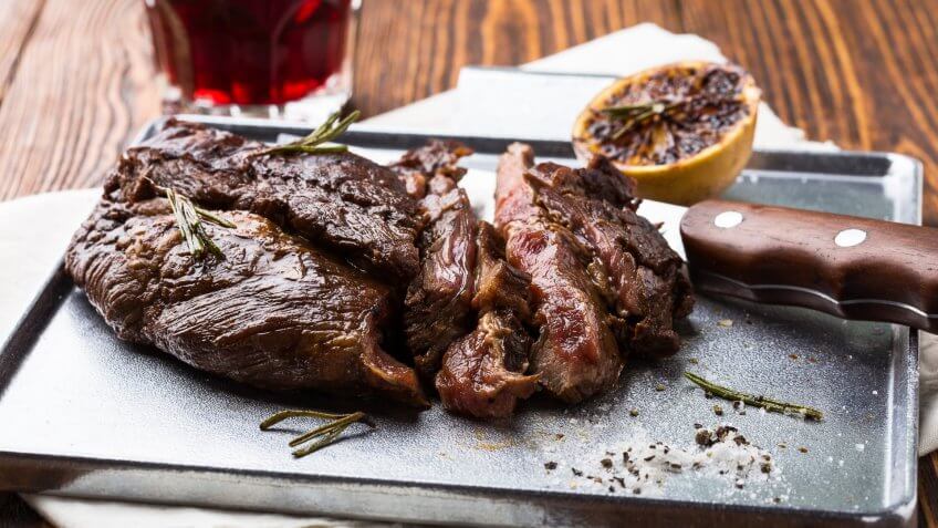 Flank steak cooked next to a knife and lemon