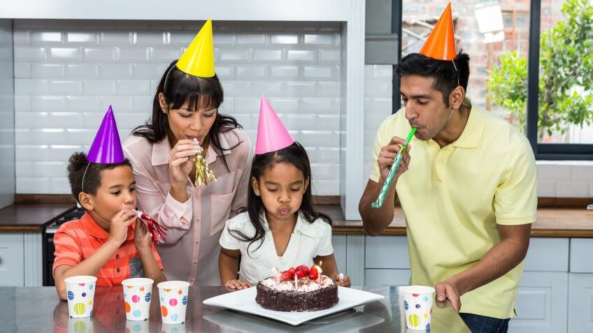 family celebrating daughters birthday with cake and hats